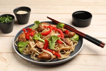 Delicious noodles with meat and vegetables served on light wooden table, closeup