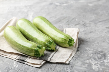 Fresh ripe zucchinis on grey textured table, closeup. Space for text