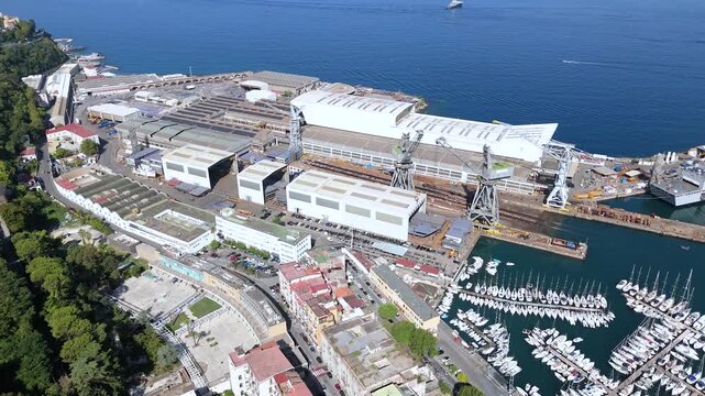 Aerial view of the Fincantieri Shipyard in Castellammare di Stabia, an important industrial hub for shipbuilding, with the port, docks, and the Gulf of Naples in the background. Italy.