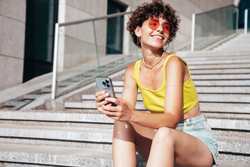 Young beautiful smiling hipster woman in trendy summer clothes. Carefree woman with curls...