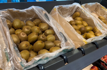 Close up of many green and golden kiwi fruits in basket at grocery store 