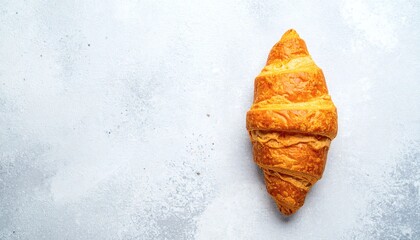 Golden Croissant with Flaky Layers on Textured Light Gray Background