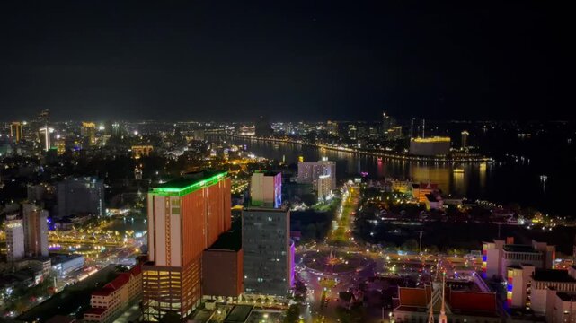 Scenic night view of Phnom Penh, Cambodia, with the skyline glowing above the Tonle Sap River, calm reflections, and colorful evening light in Southeast Asia