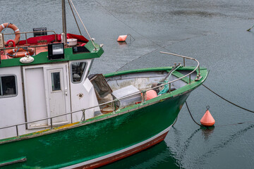 Traditional Green Fishing Boat Moored In Harbor With Orange Buoys. Commercial Fishing Vessel, Maritime Industry, Coastal Village, Working Boat At Anchor © ikuday