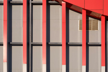 Geometric lines pattern background of red shading fins and aluminium composite tiles with sunlight and shadow on gray modern exterior building wall decoration in minimal design