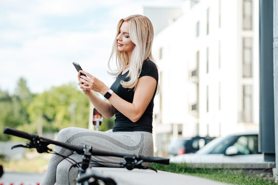 Woman using smartphone outdoors with bicycle