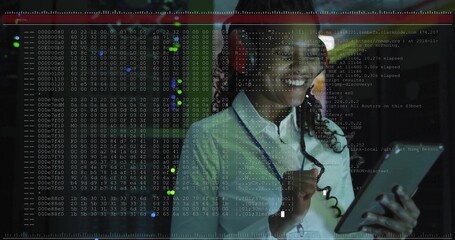 Smiling woman wearing red headset holding tablet at tech workspace, with code overlays, copy space