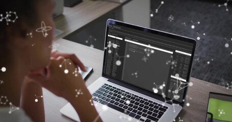 Reviewing mid adult woman examining terminal windows on laptop at workspace, with network overlays