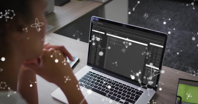 Reviewing mid adult woman examining terminal windows on laptop at workspace, with network overlays - Powered by Adobe