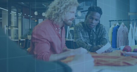 Two designers leaning over table selecting fabric swatches in design studio, with garment samples