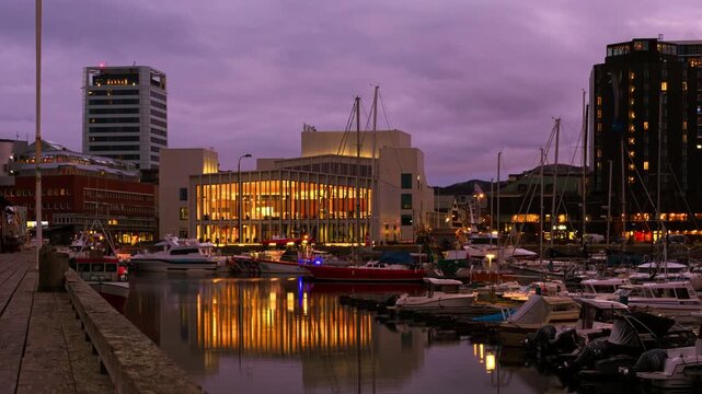 Bodo, Norway. View of the marina in the city center of Bodo, Norway with modern buildings at the background. Time-lapse at sunset. Panning video