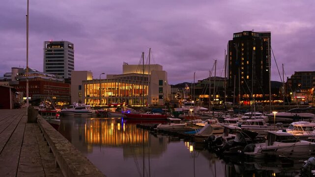 Bodo, Norway. View of the marina in the city center of Bodo, Norway with modern buildings at the background. Time-lapse at sunset. Zoom in
