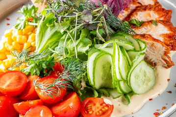 Fresh salad with grilled chicken breast, leafy greens, cherry tomatoes, cucumber, corn, red onion, herbs, and creamy dressing. Healthy, colorful, and appetizing meal