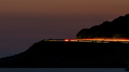 Long Exposure Night Traffic Lights on Coastal Road at Sunset