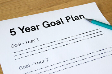Extreme close-up of a sheet with a headline '5 Year Goal Plan', with a pencil pointing to the headline