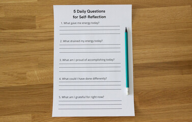 Sheet of paper lying straight on the table with a pencil. The sheet titled '5 Daily Questions of Self-Reflection', therapy session, self-awareness concept