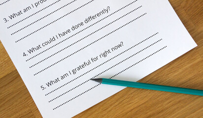 A sheet of paper with self-reflection questions. The pencil points at the question 'What am I grateful for right now?'. Self-reflection concept, self-awareness concept, psychology, mindfulness