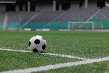 Soccer ball sits near the corner of a well-maintained football field in a modern stadium, ready for play.
