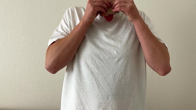 A person spilling food on white t-shirt, standing in front of a white background