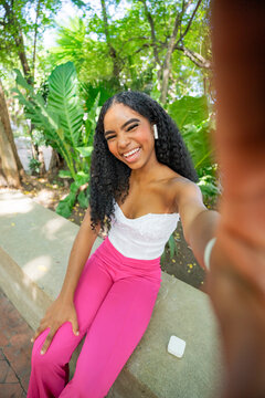 Gen Z woman with curly hair taking a selfie outdoors