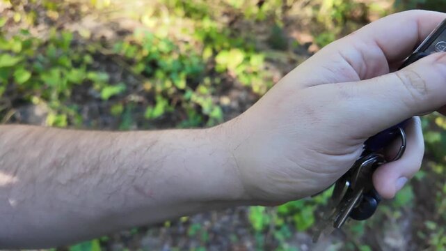 In a man's hand the alarm key fob, when the button is pressed, a red LED lights up, signaling that the protected object has been alarmed. Closeup.