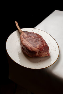 Raw tomahawk steak on an elegant white plate