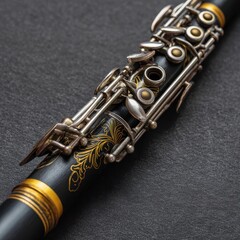 Obraz premium Detailed view of a black clarinet adorned with gold accents, resting on a dark gray surface. The image highlights the instrument's intricate details and design.