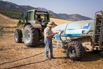 Senior man and asian woman irrigating olive grove