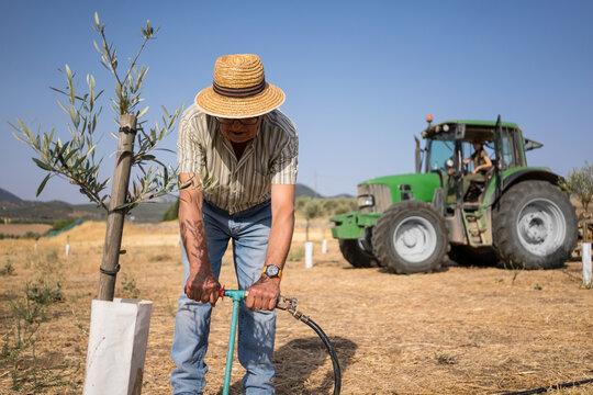 Senior man and young woman working on tractor irrigation - Powered by Adobe
