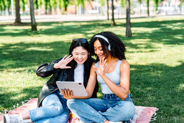 Friends enjoying video chat on tablet in the park