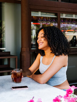 Gen Z black woman enjoying a refreshing drink outdoors