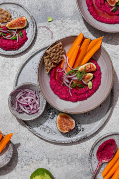 Top view of beet hummus with vegetables and figs