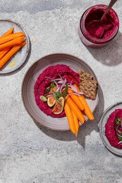 Top view of beet hummus dip with carrots and figs