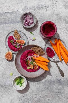 Top view of vibrant beet hummus with fresh vegetables and figs