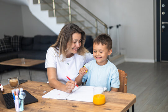 Mother and young son using laptop and a notebook at home