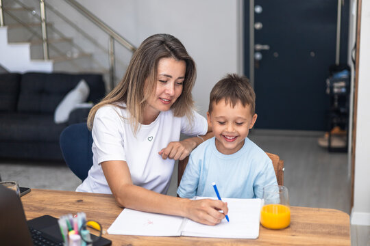 Mother and son using a laptop and a notebook at home