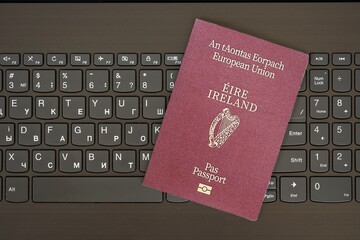 Ireland passport lies on black laptop keyboard buttons background . Technologies in Europe