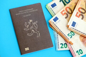 Luxembourg passport lies with euro money banknotes on blue background. Salary and pension in Europe