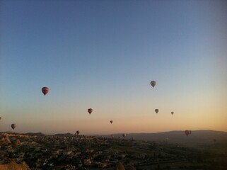 Hot Air Balloons Over Town and Rock Formations at Sunrise in Cappadocia, Turkey