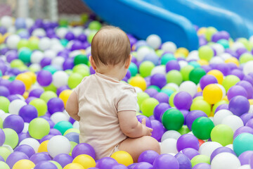 Obraz premium Baby sitting in colorful plastic ball pit. Early development