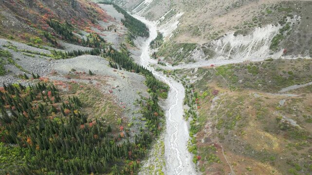 Autumn view of mountains and river in Ala Archa National Park, Kyrgyzstan, with golden and rocky slopes.