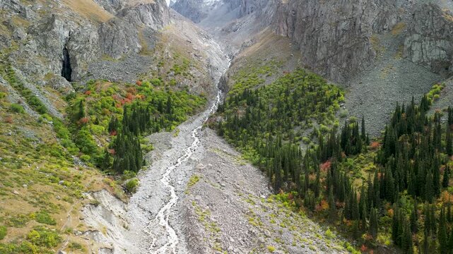 Autumn view of mountains and river in Ala Archa National Park, Kyrgyzstan, with golden and rocky slopes.