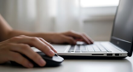 Hands navigate laptop and mouse during remote work from comfortable space