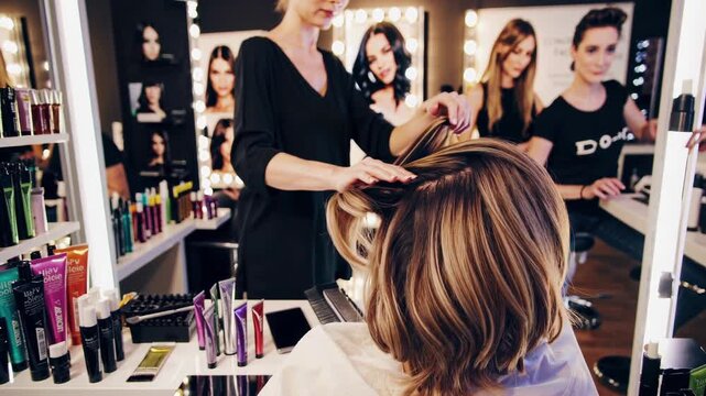 Skilled hairdresser carefully styling client's hair, creating elegant waves and curls in contemporary salon environment with professional beauty tools and cosmetics surrounding workspace
