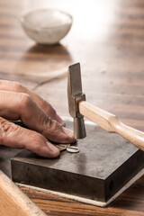 jeweler working with a hammer and silver earrings