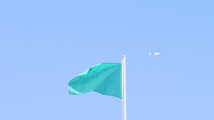 A vibrant green flag waving proudly against the backdrop of a beautiful clear blue sky
