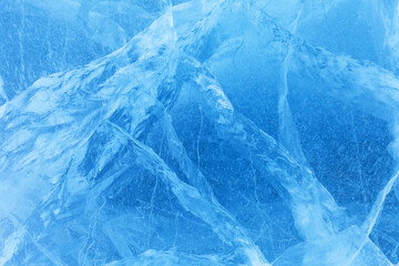 Amazing natural ice texture. Cold blue ice background with cracks and lines on surface of frozen Lake Baikal in winter. Unique ice pattern. Top view, closeup, flat lay, Christmas blank, copy space