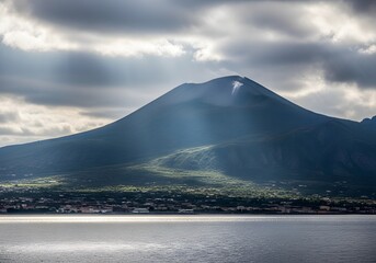 Majestic volcano looming over a coastal town under dramatic cloudy skies