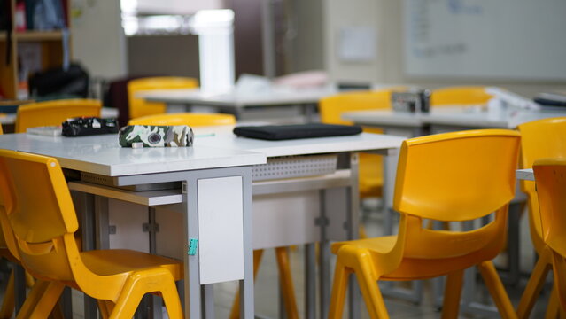 An empty classroom filled with yellow chairs and tables ready for learning