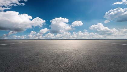 empty asphalt parking lot under a bright blue sky with fluffy clouds